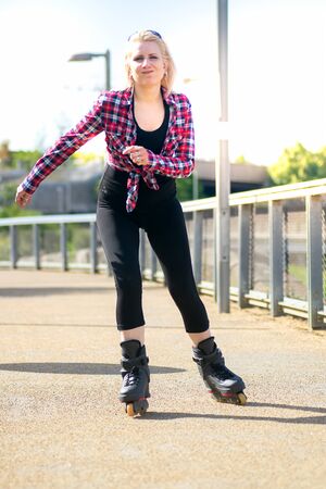 Blonde woman roller skating on the pavement outdoorsの写真素材
