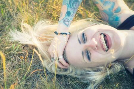 Young blonde woman laughing laying in the grassの写真素材