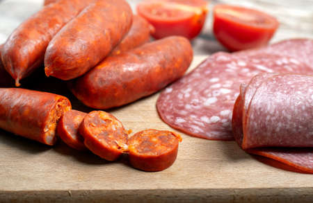 Chorizo sausages and salami slices on a wooden boardの写真素材