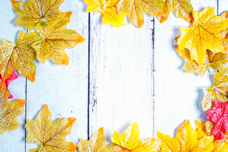 Wooden background framed with colourful autumn leavesの写真素材
