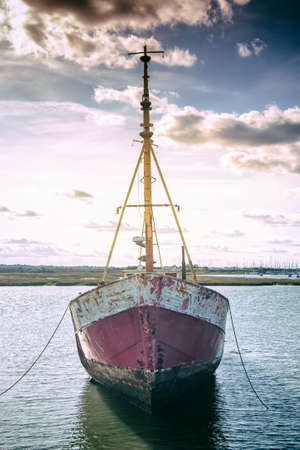 Old rusty boat anchored in the riverの写真素材