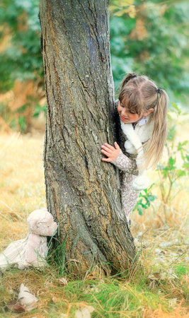Little girl playing hide and seek with a teddyの写真素材