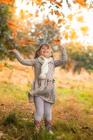 Happy little child playing with leaves at autumn timeの写真素材