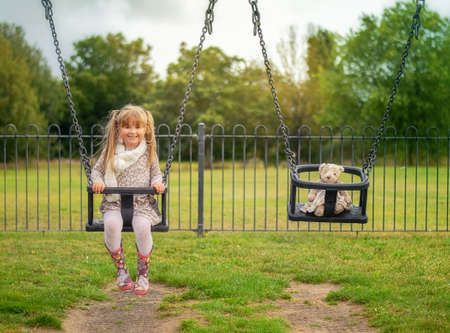 Little girl on the swing with a teddy bearの写真素材