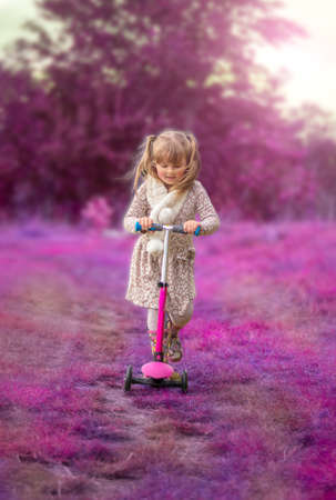 Little girl on a scooter in a fantasy natureの写真素材