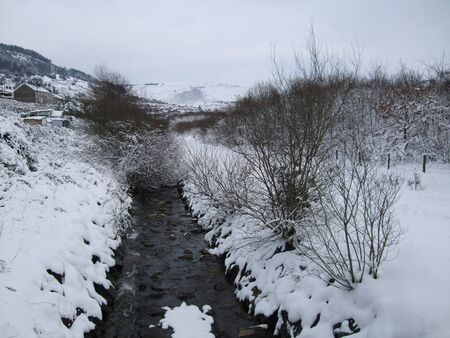 A stream in South Wale surrounded by a snowy landscapeの写真素材