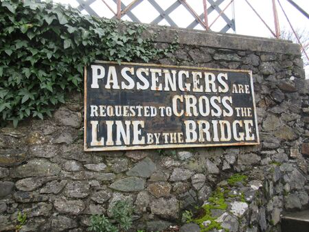 Old railway sign on heritage line "Passengers are requested to cross the line by the bridge"の写真素材