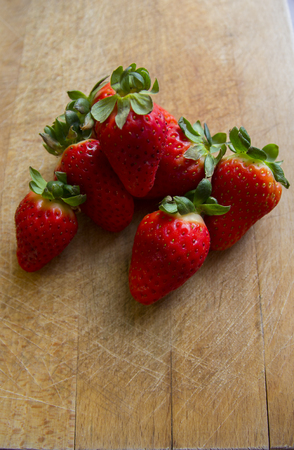 Pile of strawberries on wooden cutting boardの写真素材
