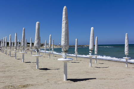 Closed beach umbrellas on a beach of Salentoの写真素材