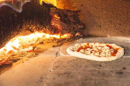 Italian pizza baking in stone oven. Burning wood in the backgroundの写真素材