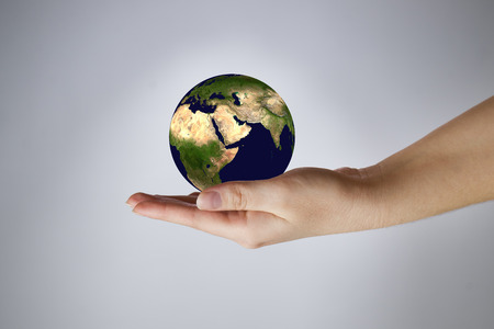 The Earth in a female hand. Gray background. 3D render.の写真素材