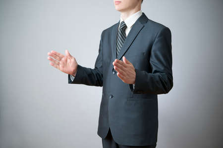 Business man in suit on gray background. Gesture with his handsの写真素材