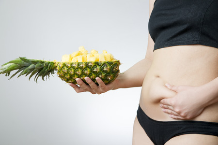 Young woman's body with pineapple on gray background. Weight loss, dietの写真素材