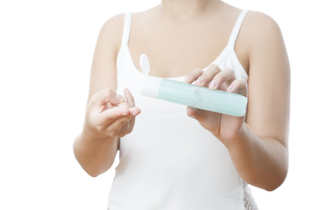 Bottle with cream in a female hand. Isolated on a white background.の写真素材