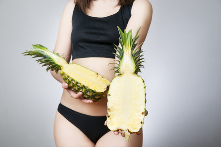 Overweight of the women with pineapple. Young female body on gray background. Weight loss, dietの写真素材