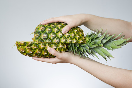 Pineapple in female hands on gray background. Weight loss, dietの写真素材