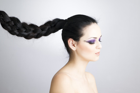 Portrait of a beautiful young woman on a gray background. Hair braided in a braid. Professional make-up and hairstyle.の写真素材