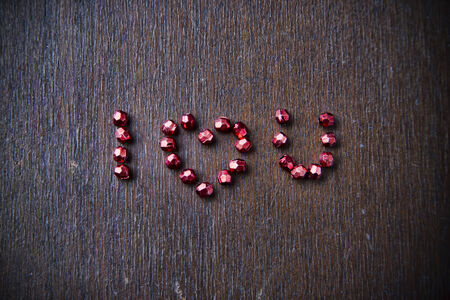 Background for Valentine's day. Heart shape in a  heap of beads.  I love you. Wooden pattern. Retro style.の写真素材
