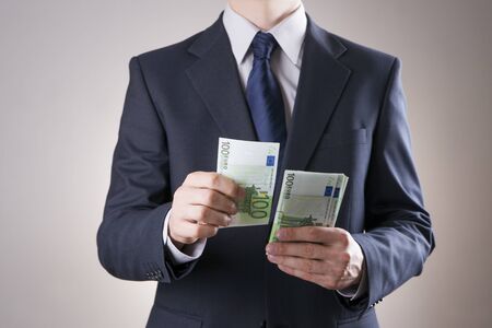 Businessman with money in studio on a gray backgroundの写真素材