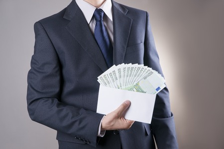 Money in an envelope in the hands of men on gray backgroundの写真素材