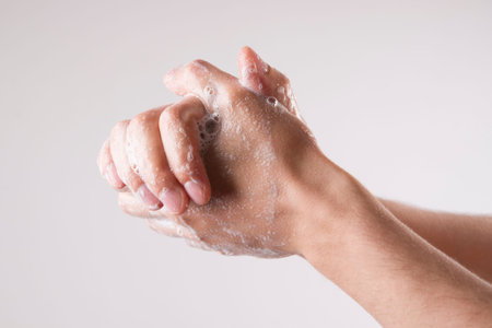 A man washes his hands with soap and water on a gray background