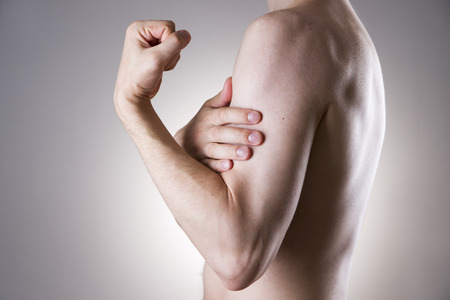 Man with pain in arm. Pain in the human body on a gray backgroundの写真素材