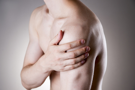Man with pain in shoulder. Pain in the human body on a gray backgroundの写真素材