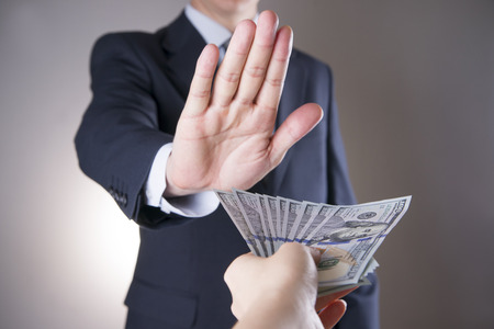 Businessman with money in studio on a gray background. Corruption concept. Hundred dollar billsの写真素材