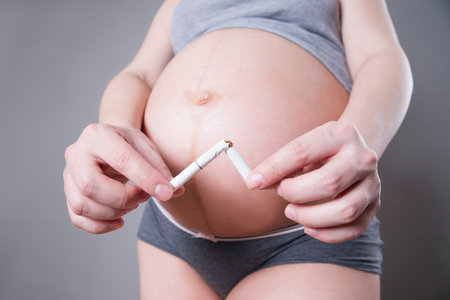 Pregnant woman quits smoking. Studio shot on a gray background. Health care concept