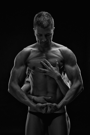 Nude sexy couple. Art photo of young adult man and woman. High contrast black and white muscular naked body on black backgroundの写真素材
