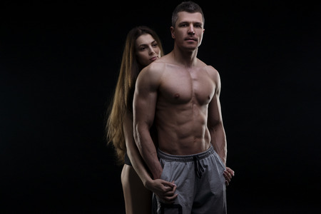 Young adult muscular man and woman. Sexy couple on black backgroundの写真素材