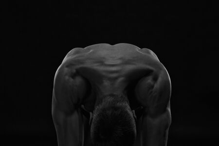 Handsome muscular bodybuilder posing on black background. Low key studio shot. Sexy male bodyの写真素材