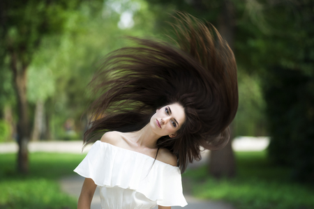 Portrait of a beautiful young caucasian woman with flying long hair, clean skin and casual makeup, nature backgroundの写真素材
