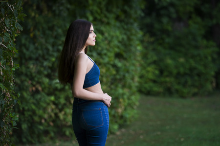 Portrait of a beautiful young caucasian woman in blue jeans and denim top, clean skin, long hair and casual makeup, nature backgroundの写真素材
