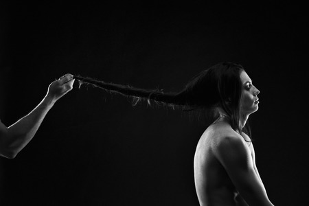 Art photo of young adult woman, black and white muscular naked body on black background, domestic violence conceptの写真素材