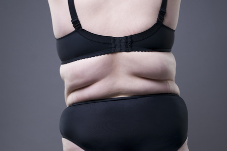 Plus size model in black lingerie, overweight female body, fat woman with cellulitis on buttocks posing on gray backgroundの写真素材