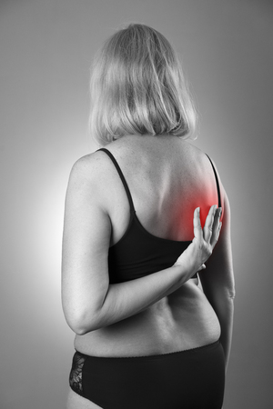 Back pain, massage of female body, ache in woman's body, black and white photo with red spotsの写真素材
