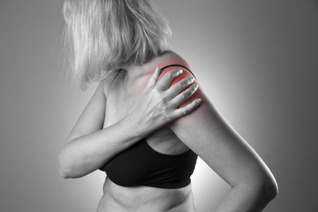 Pain in shoulder, care of female hands, ache in woman's body, black and white photo with red spotsの写真素材