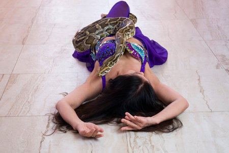 Adult woman in blue stage costume performs with big snakeの写真素材