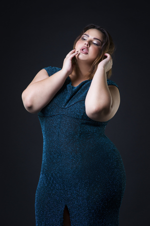 Plus size fashion model in green evening dress, fat woman on black studio background, portrait with professional makeupの写真素材