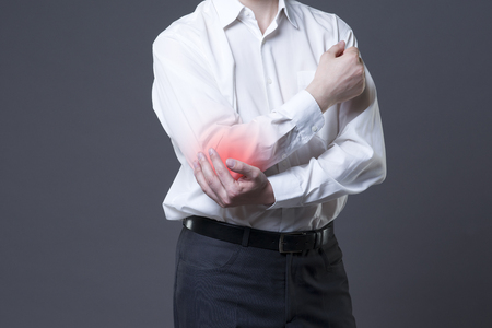 Pain in elbow, joint inflammation, studio shot with red dot on gray backgroundの写真素材