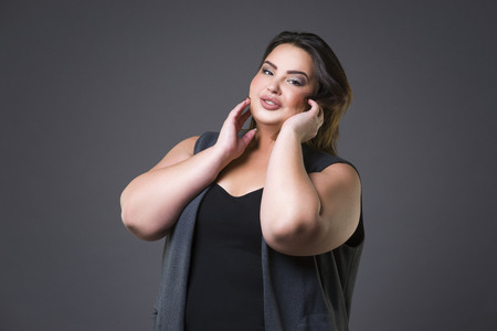 Plus size fashion model in casual clothes, fat woman on gray studio background, overweight female bodyの写真素材