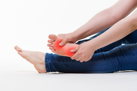 Pain in woman's legs, massage of female feet on white background, studio shotの写真素材