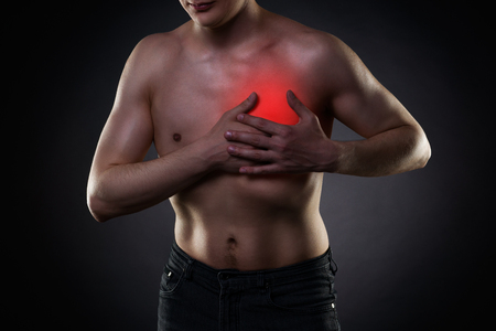 Heart attack, man with chest pain on black background with red dotの写真素材