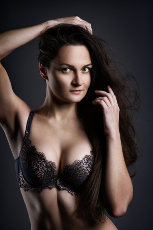 Beautiful sexy woman in lingerie posing on gray studio background, perfect female body, low key studio shotの写真素材