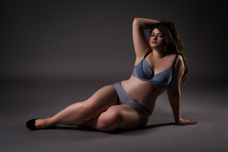 Plus size sexy model in underwear, fat woman on gray studio background, overweight female body, full length portraitの写真素材