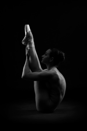 Art nude, perfect naked body, sexy young woman on dark background, black and white photography, studio shotの写真素材