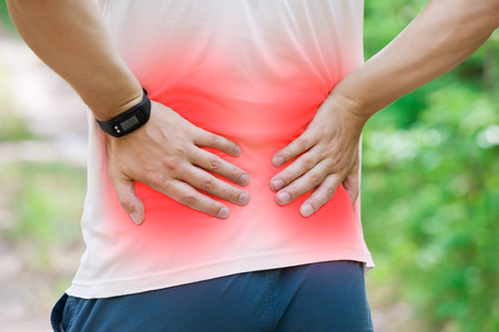 Man with back pain, kidney inflammation, trauma during workout, outdoors conceptの写真素材