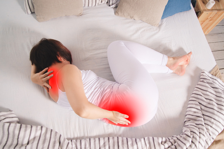 Back pain, kidney inflammation, woman suffering from backache at home, painful area highlighted in redの写真素材