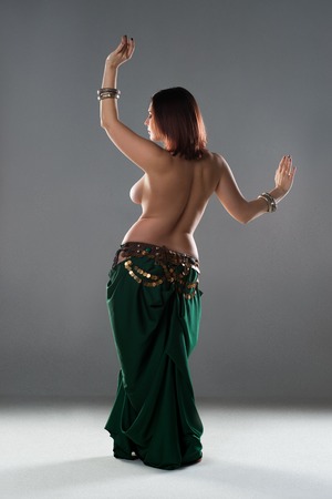 Sexy women performs belly dance in ethnic dress on gray background, studio shotの写真素材